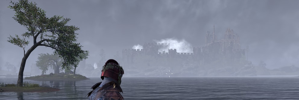 In the distance across the lake a castle is visible, clouds rolling over the top of the towers and partially hidden in the mist.
